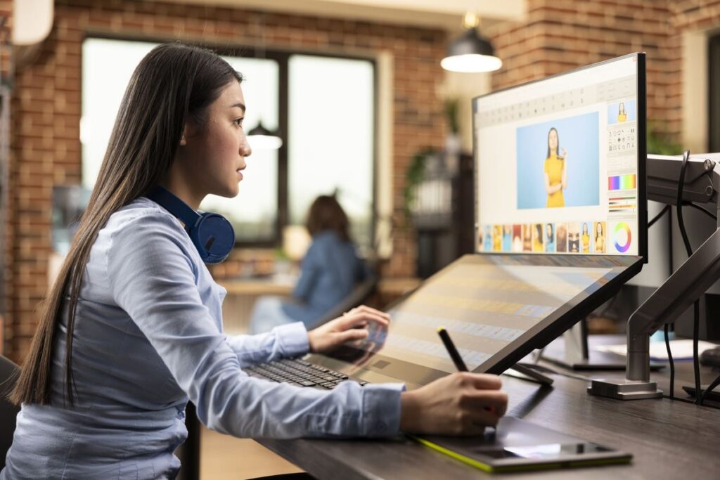 Profissional utilizando caneta digital e tela interativa para edição de imagens, representando um curso de Design Gráfico.