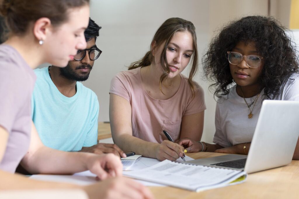 Grupo de universitários estudando em equipe com notebook, representando dúvidas e aprendizados sobre o que é citações e normas ABNT.