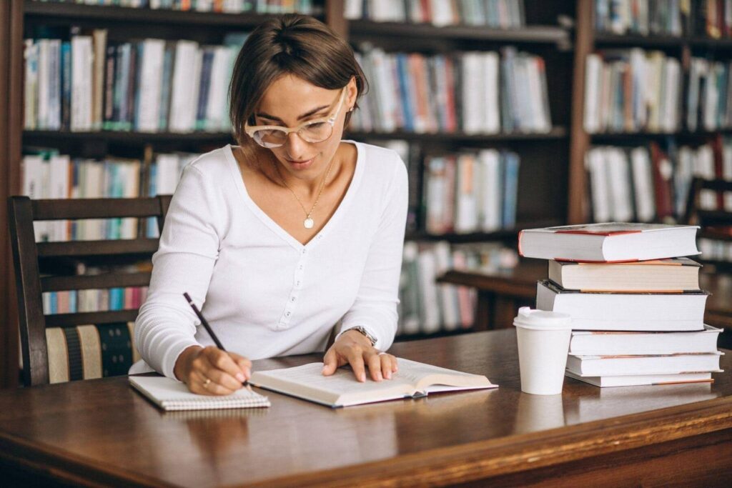  Pessoa pesquisando e fazendo anotações na biblioteca.