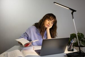Estudante cansada dormindo sobre a mesa de estudos.