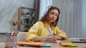 Menina estudando em casa enquanto escuta música para melhorar a concentração e o foco.
