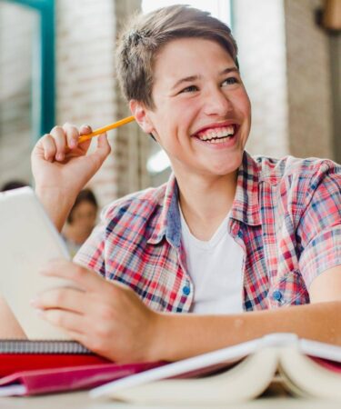 Jovem sorrindo enquanto segura tablet, mostrando de forma leve o que é vestibular e como a tecnologia pode auxiliar na preparação.