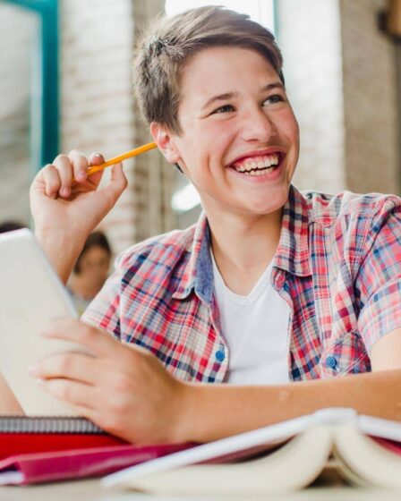 Jovem sorrindo enquanto segura tablet, mostrando de forma leve o que é vestibular e como a tecnologia pode auxiliar na preparação.