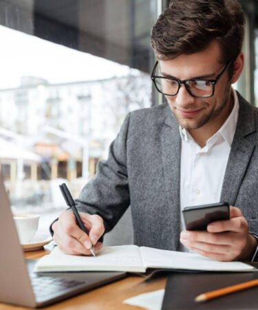 Homem pesquisando e fazendo anotações sobre qual a diferença entre MBA e pós-graduação.