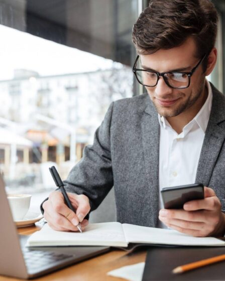 Homem pesquisando e fazendo anotações sobre qual a diferença entre MBA e pós-graduação.