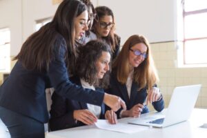 Equipe em reunião analisando no notebook qual a diferença entre MBA e pós-graduação.