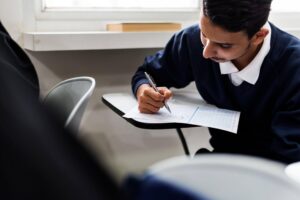 Jovem estudante preenchendo o gabarito durante prova em sala de aula, ilustrando o passo a passo de como se inscrever no Enem.