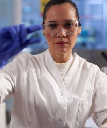 Pesquisadora analisa amostra de sangue em laboratório, mostrando na prática o que é Biomedicina e sua atuação em laboratórios.