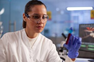 Biomédica observa tubo de ensaio durante análise clínica em laboratório, exemplificando o que é Biomedicina na área da saúde.