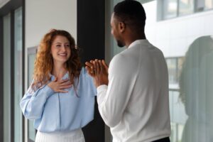 Homem e mulher conversando de forma amigável em ambiente corporativo, representando o que é relacionamento interpessoal entre colegas de trabalho.