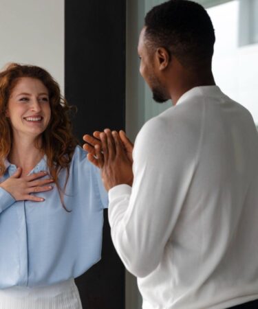 Homem e mulher conversando de forma amigável em ambiente corporativo, representando o que é relacionamento interpessoal entre colegas de trabalho.
