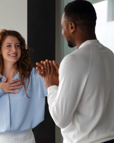 Homem e mulher conversando de forma amigável em ambiente corporativo, representando o que é relacionamento interpessoal entre colegas de trabalho.