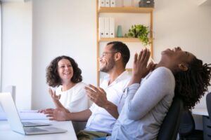 Equipe de trabalho sorrindo e conversando, demonstrando integração, comunicação no ambiente corporativo, exemplo de o que é relacionamento interpessoal