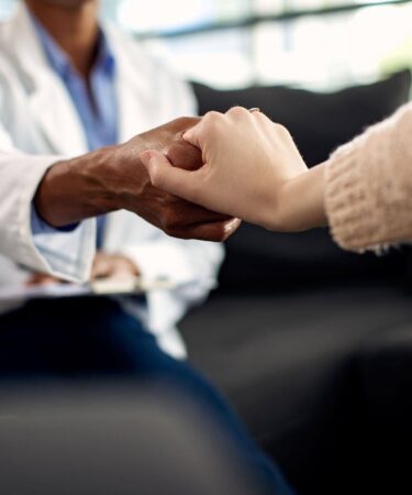 Psicólogo clínico segura a mão de uma paciente durante uma consulta, transmitindo acolhimento, empatia e apoio emocional.