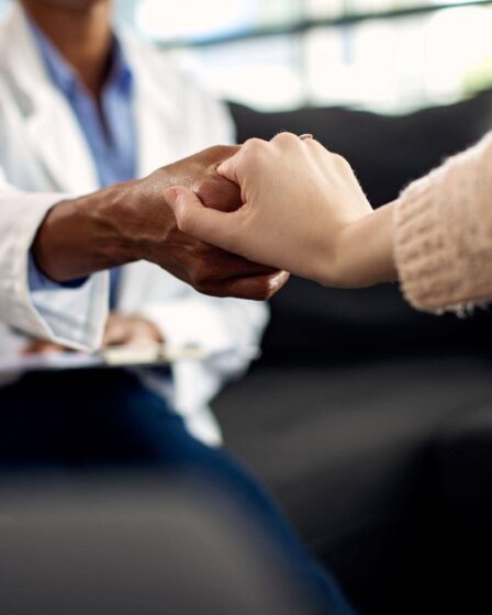 Psicólogo clínico segura a mão de uma paciente durante uma consulta, transmitindo acolhimento, empatia e apoio emocional.