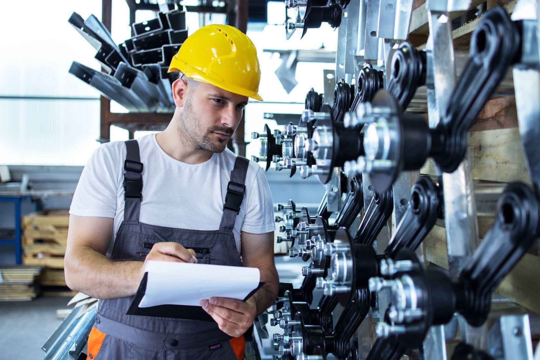 Especialista em Engenharia de Produção inspecionando componentes industriais e registrando informações para controle de qualidade em ambiente fabril.