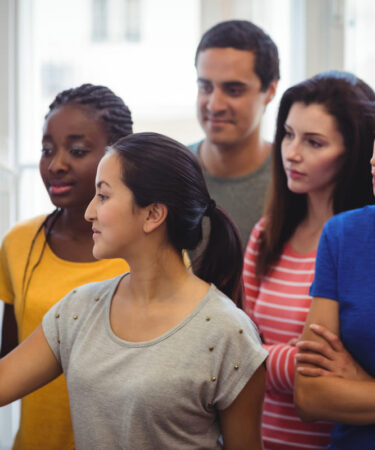 Estudantes reunidos em frente a um quadro colaborando em uma atividade em grupo, ilustrando o aprendizado de Sociologia por meio da troca de conhecimentos.