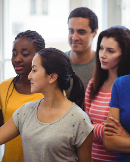 Estudantes reunidos em frente a um quadro colaborando em uma atividade em grupo, ilustrando o aprendizado de Sociologia por meio da troca de conhecimentos.