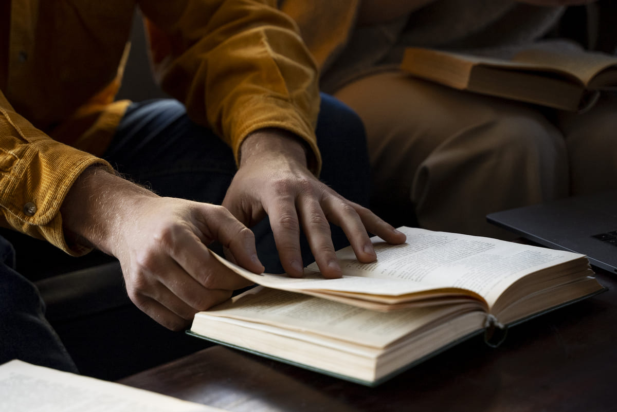 Mãos folheando a Bíblia durante uma sessão de estudos, representando o que é teologia e o aprofundamento no conhecimento das Escrituras.