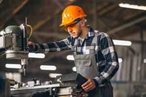 Profissional da Engenharia de Fabricação Mecânica operando máquina-ferramenta com equipamentos de proteção individual em ambiente de manufatura industrial.