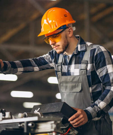 Profissional da Engenharia de Fabricação Mecânica operando máquina-ferramenta com equipamentos de proteção individual em ambiente de manufatura industrial.