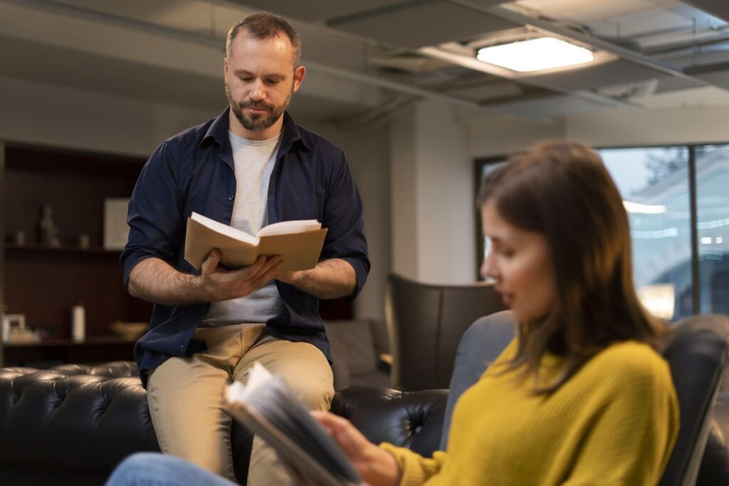 Homem e mulher lendo livros em um ambiente de estudo, ilustrando o que é Teologia e a importância da leitura para a compreensão dessa área.