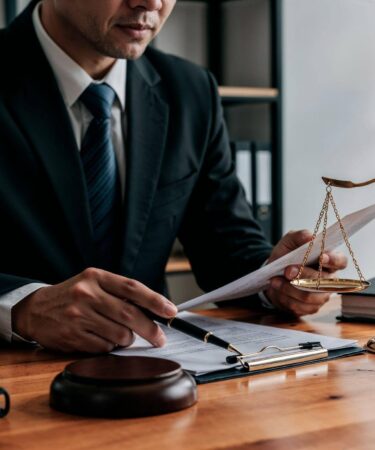 Advogado analisando documentos ao lado de uma balança da justiça em escritório, representando atuação e consultoria em Direito Administrativo.