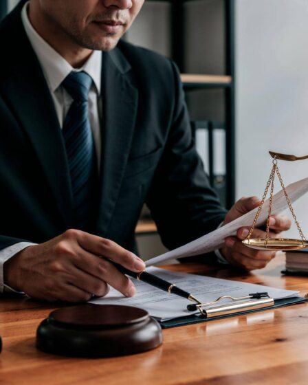Advogado analisando documentos ao lado de uma balança da justiça em escritório, representando atuação e consultoria em Direito Administrativo.