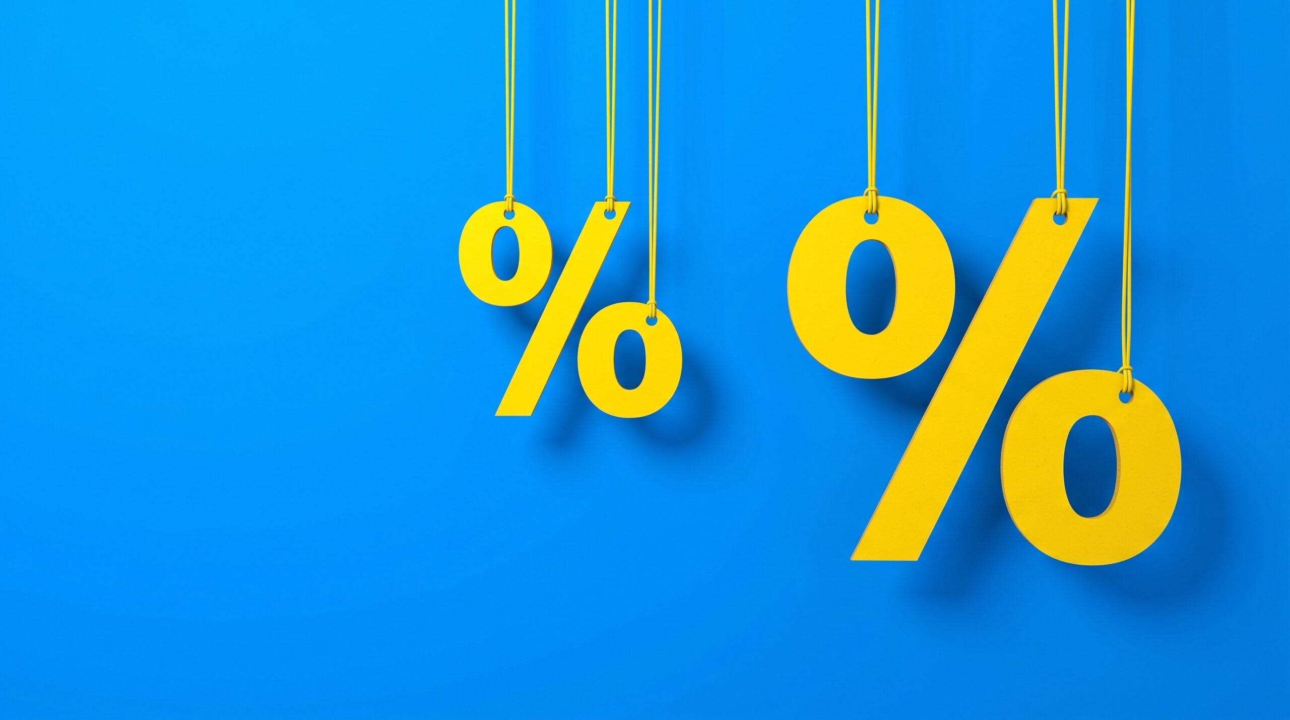 Símbolos de porcentagem amarelos pendurados por fios em um fundo azul vibrante, ilustrando os descontos e as ofertas especiais da Black Friday da Uninter.