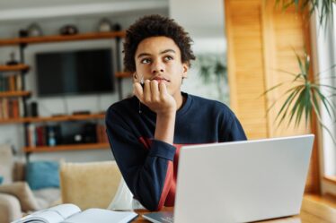 estudante em uma sala em frente ao notebook.